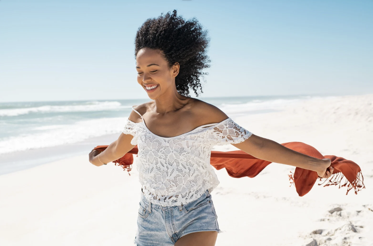 african-american woman on the beach, on vacation after using a travel agent